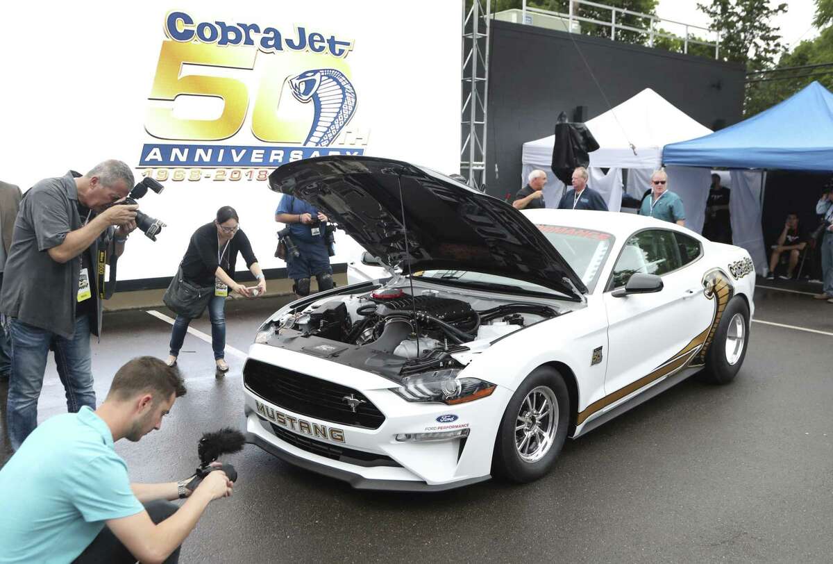 In this Aug. 16, 2018 photo, journalists photograph the new 2018 Ford Cobra Jet Mustang, in Royal Oak, Mich. Muscle car fans consider the Ford Mustang, Chevrolet Camaro and Corvette and the Dodge Challenger and Charger to be the mainstays of Detroit performance cars. But their combined sales fell 7 percent in 2016, 11 percent last year, and are down almost 10 percent for the first half of 2018, according to numbers provided by Kelley Blue Book.