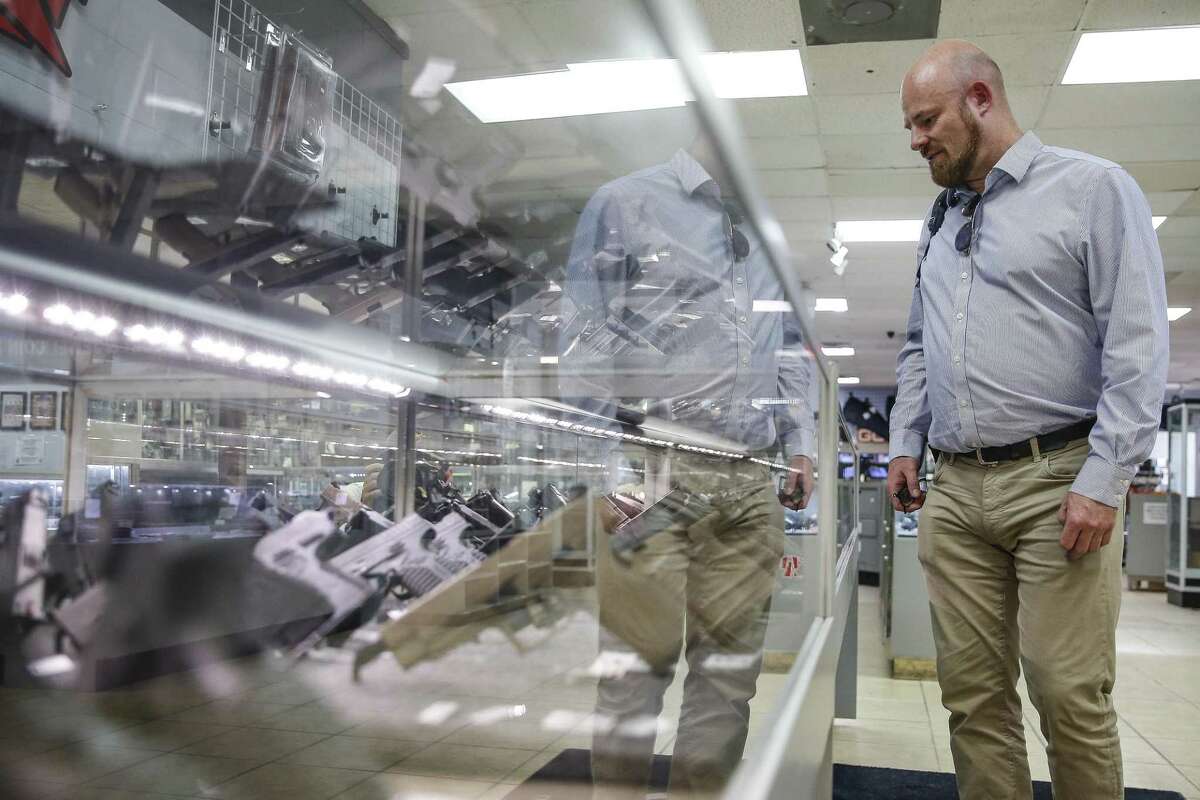 Dave Thompson, from the UK, looks at a case full of handguns at Full Armor Firearms Thursday Sept. 6, 2018 in Houston. After demand for firearms reached record highs on the night of the 2016 election, sales have fallen off sharply in what manufacturers are calling the Trump slump.