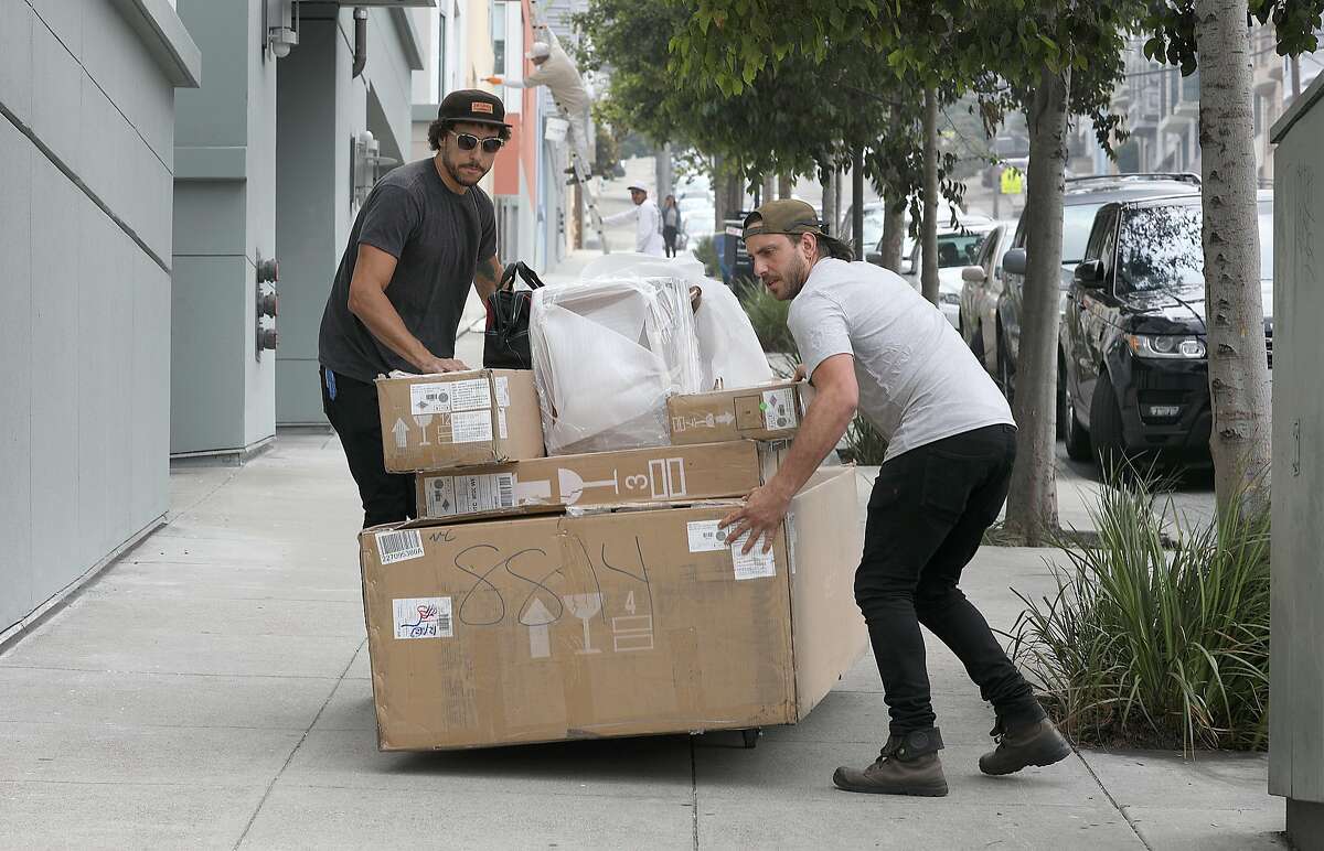 Delivery leads Chris Ledet (left) and Jake Gonen (middle) move household furniture from Feather to an apartment on Kansas St. on Thursday, Aug. 23, 2018 in San Francisco, Calif. SF startup Feather rents household furniture to people on a subscription plan.