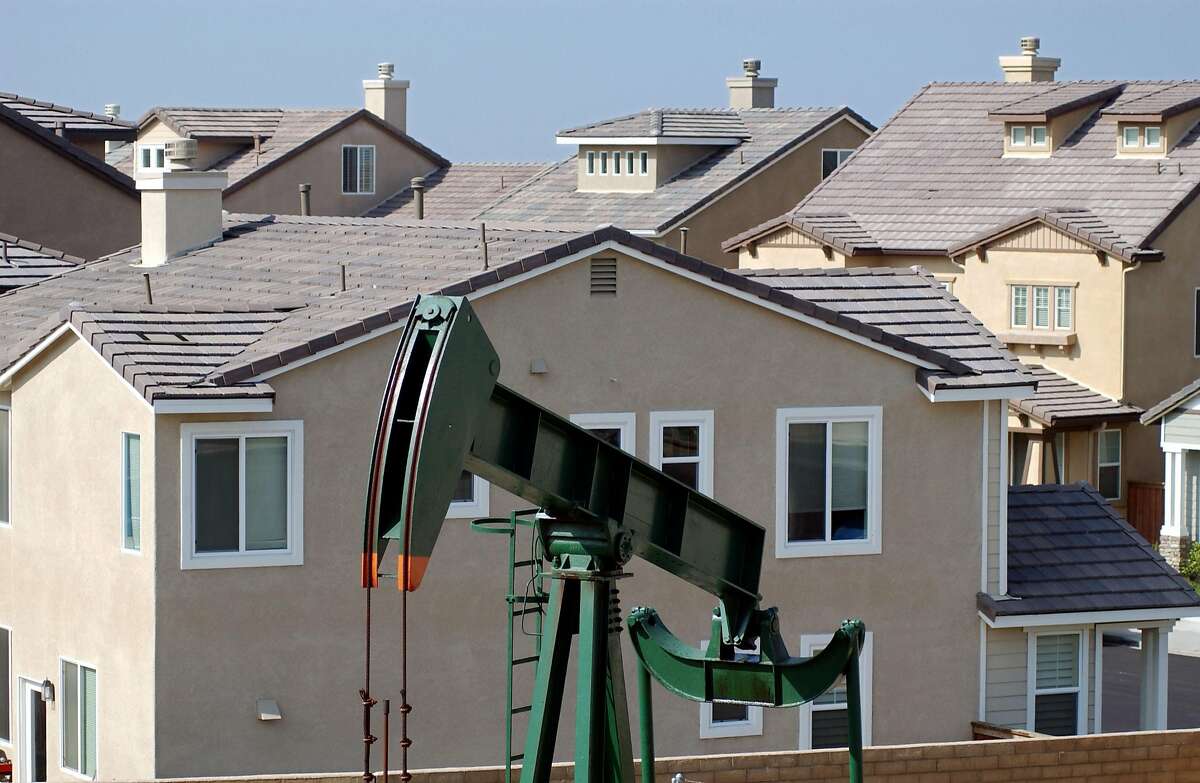 LONG BEACH, CA - MAY 30: An oil well pumps in a newly constructed neighborhood near Shell Oil Company Alamitos No. 1 discovery well on Signal Hill on May 30, 2003 in Long Beach, California. Alamitos No. 1 was created in 1921 and helped establish California as one of the world's major oil-producing states. The Signal Hill Oil Field, now known as the Long Beach Oil Field, reportedly had the world's highest oil production per acre by the mid-twentieth century. Hundreds of companies and individuals became rich on minute leases, some locations so close that derrick legs overlapped. New housing and stores are now being built among operating oil wells. Farther north, a cancer scare has swept over Beverly Hills High School where environmental activist Erin Brockovich and her boss, lawyer Ed Masry, are alleging that toxic fumes from oil wells on the campus have created a "cancer cluster" that is 20 times higher than the national average. (Photo by David McNew/Getty Images)