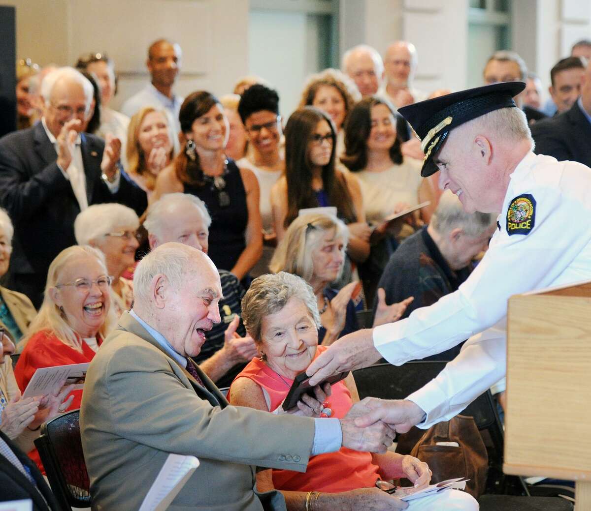 With his wife Dolly, center, looking on, John Margenot smiles as Greenwich Police Chief Jim Heavey gives Margenot a photo of when Margenot, serving as Greenwich First Selectman, swore Heavey in as a police officer during a ceremony and dedication of the John Margenot Atrium in his honor at the Public Safety Complex in Greenwich, Conn., Saturday, Sept. 8, 2018. Margenot, a former long-serving Greenwich First Selectman is now 90 years-old and still works as a town volunteer.