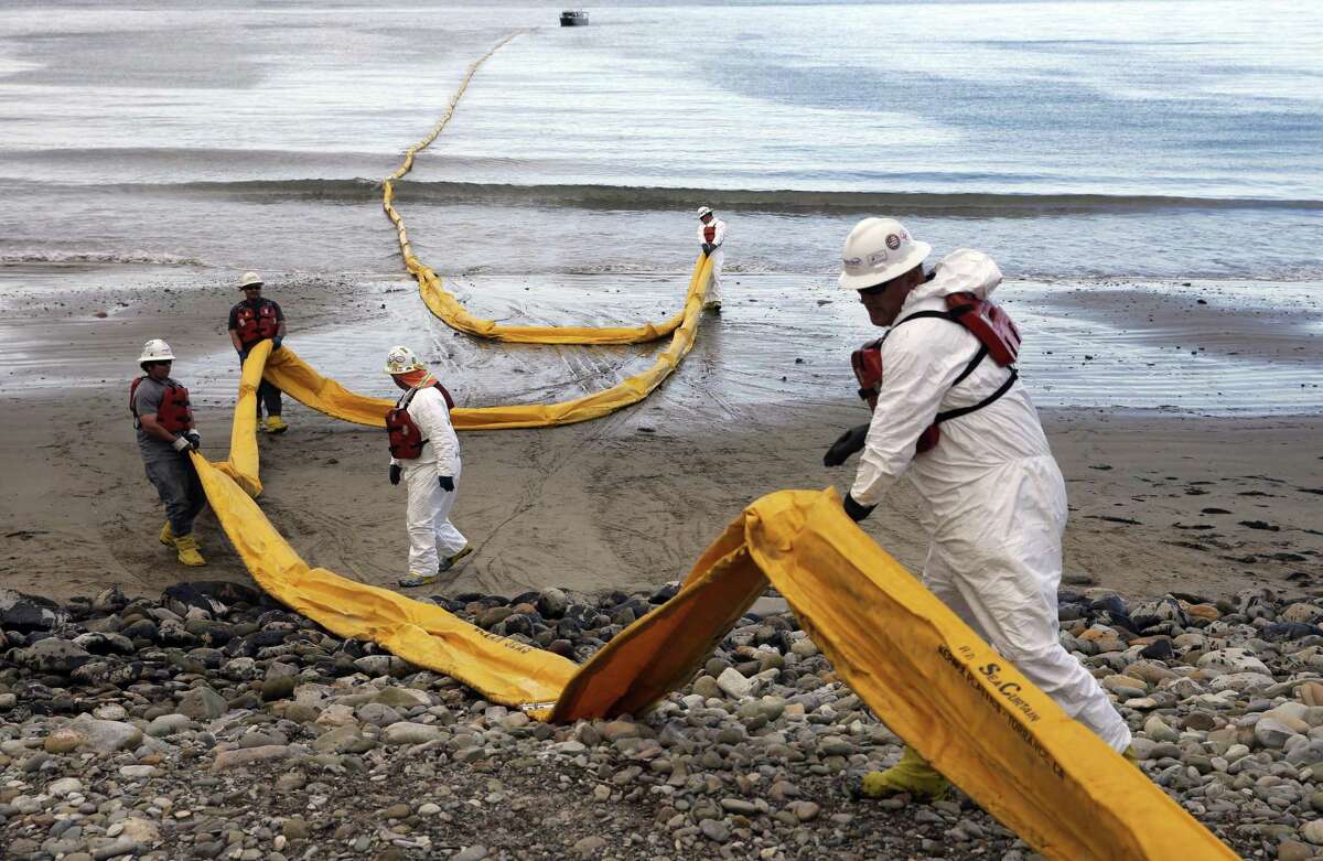 FILE - In this May 21, 2015, file photo, workers prepare an oil containment boom at Refugio State Beach, north of Goleta, Calif., two days after a ruptured pipeline created the largest coastal oil spill in California in 25 years. A California jury has found a pipeline company guilty of nine criminal charges for causing a 2015 oil spill that was the state's worst coastal spill in 25 years. The jury in Santa Barbara County reached its verdict against Plains All American Pipeline of Houston on Friday, Sept. 7, 2018, following a four-month trial. (AP Photo/Jae C. Hong, File)