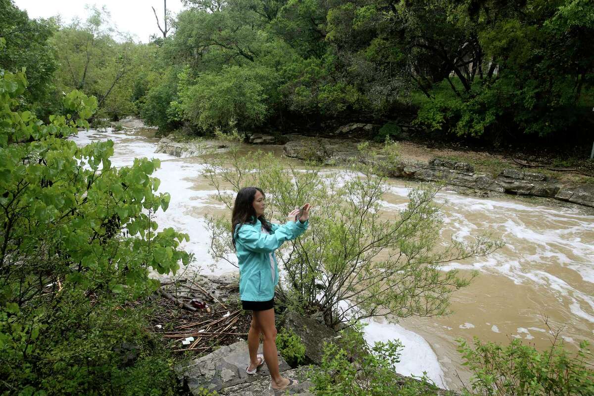 Kat Gehrke watches a flooded Helotes Creek in Grey Forest after rains causes flooding at low water crossings throughout the town, Sunday, Sept. 9, 2018. At the height of the rain storm, all low water crossings, including the main road leading into Grey Forest, Scenic Loop Road, were closed for several hours.