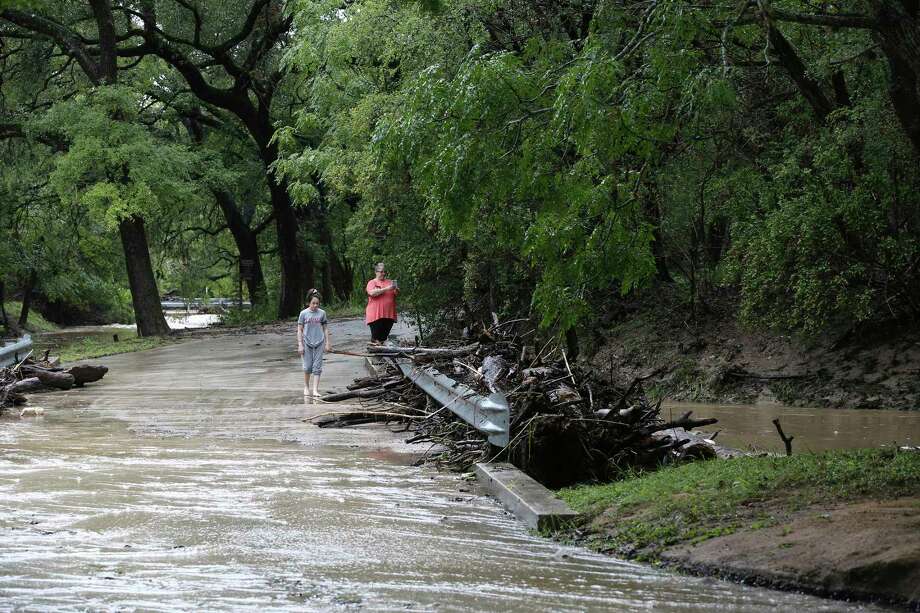 The inhabitants of the Gray Forest photograph debris at the low level crossing on Sunday, September 9, 2018. All Gray Forest crossings were closed Sunday morning due to flooding. At the height of the storm, the main road to the city, Scenic Loop Road, was closed for several hours. Photo: JERRY LARA, San Antonio Express News / © 2018 San Antonio Express-News