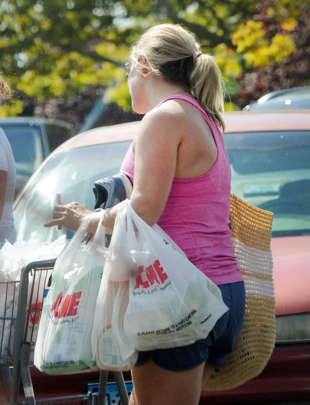 A customer carrying plastic shopping bags leaves the Riverside Commons Shopping Center in Greenwich, Conn., Tuesday, Sept. 4, 2018. A town ban on plastic bags goes into effect on Sept. 12.
