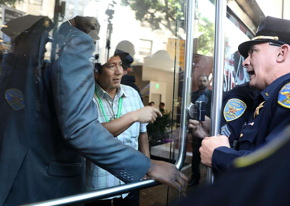 An Amazon Watch supporter (middle left) tries to get his colleagues let into the Hilton Parc 55 hotel as there is a picket along Market Street at Fifth Street and extending up Cyril Magnin Way in advance of the beginning of the Climate Summit on Monday, Sept. 10, 2018 in San Francisco, Calif.