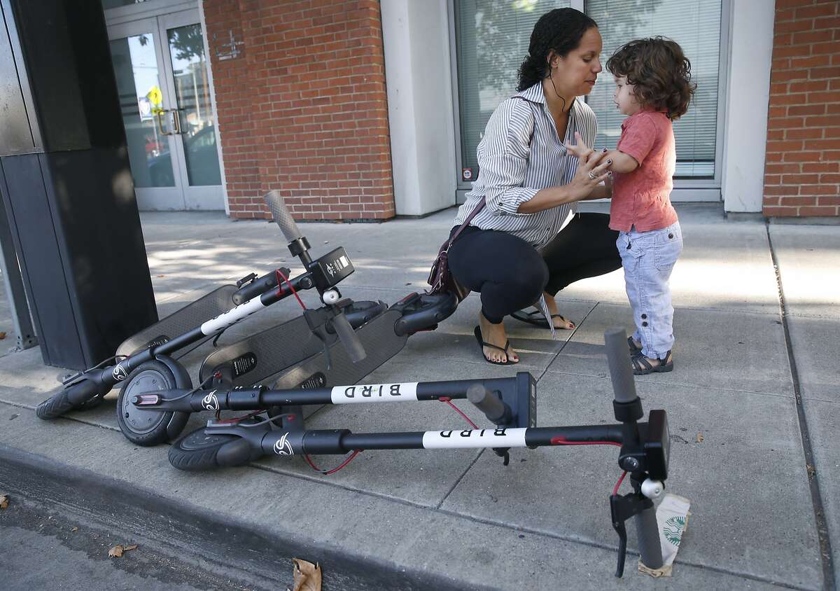 Siena Sarmiento speaks to her son Carter, 2, next to scooters lying on the sidewalk in Oakland, Calif. on Saturday, Sept. 8, 2018. Carter was knocked over and bruised when he was hit by someone riding an electric scooter as he and his mother walked out of their Grand Avenue apartment building.