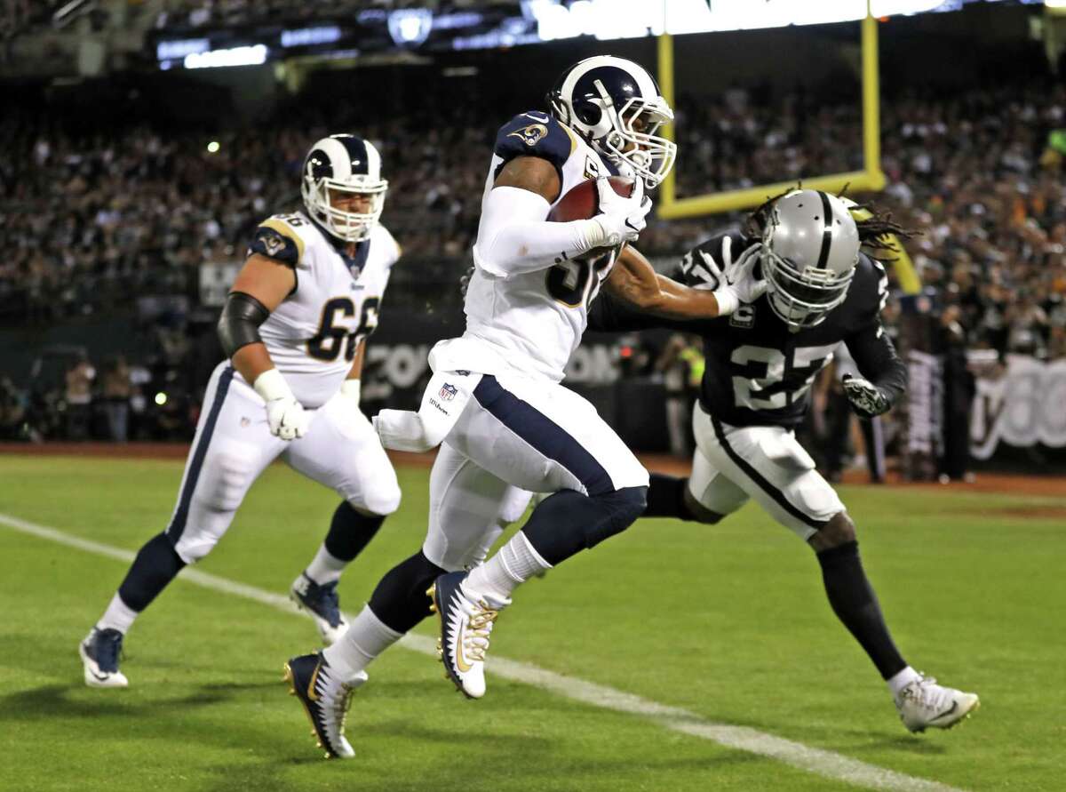 Los Angeles Rams' Todd Gurley II scores on 19-yard pass reception against Oakland Raiders' Reggie Nelson in 1st quarter during NFL game at Oakland Coliseum in Oakland, Calif. on Monday, September 10, 2018.