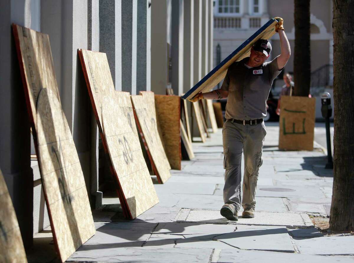 Preston Guiher carries a sheet of plywood as he prepares to board up a Wells Fargo bank in preparation for Hurricane Florence in downtown Charleston, S.C., Tuesday, Sept. 12, 2018.