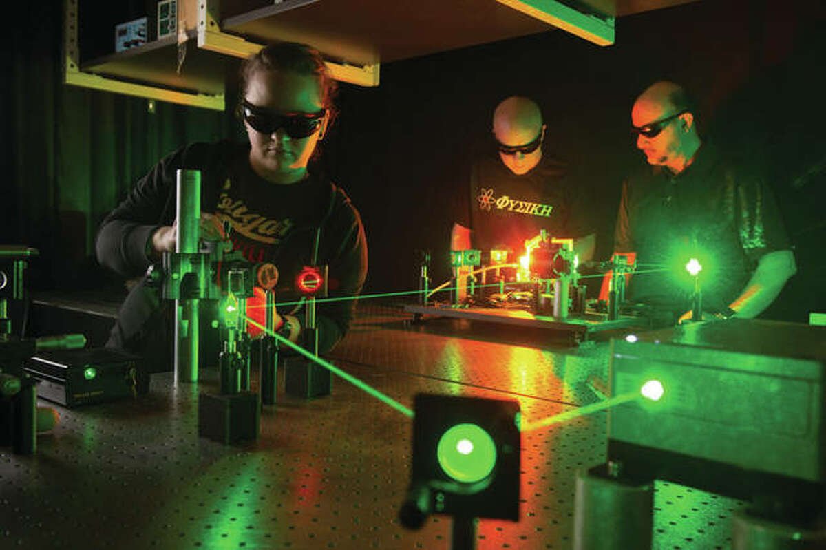SIUE students Nicole Lindsey, left, and Ronald Taylor with physics professor Abdullatif Hamad in laser lab.