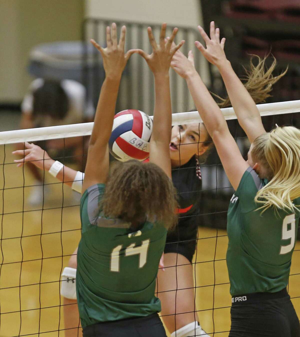 Caroline Meuth slams the ball past Kina Mond,L and Carlee Pharris from the District 27-6A high school volleyball showdown between rivals Churchill and Reagan on Tuesday, September 11, 2018.