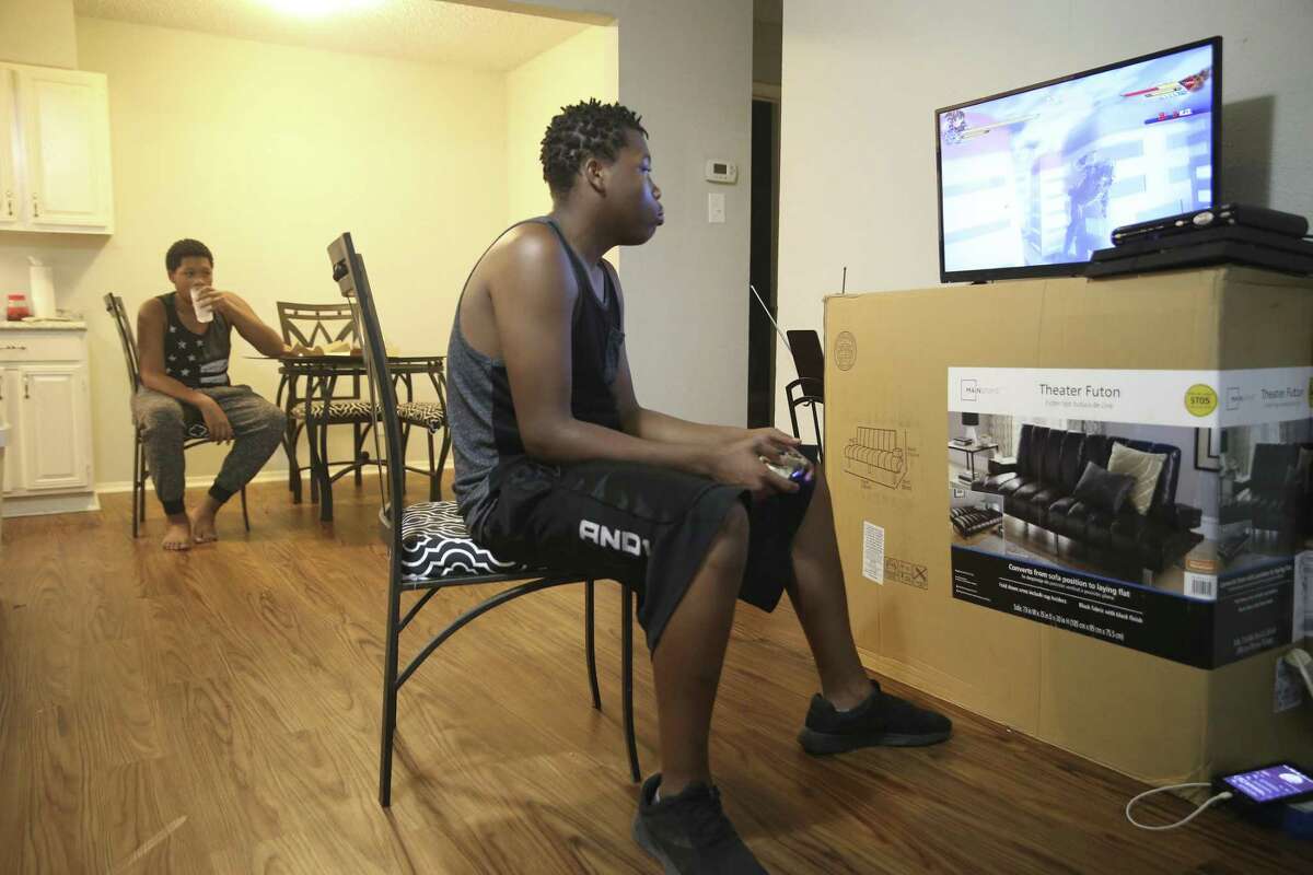 Denzel Taylor, 16, plays video games as his brother, David Veasey, 14, eats dinner at their apartment off Blanco Road inside Loop 410 on Wednesday. The brothers moved to San Antonio from Green Bay, Wisconsin, with their mother, Vanessa Taylor, 50. The family lived for a time at Haven for Hope. After Vanessa Taylor married another Haven resident, Willie H. Hicks, 58, the family was able to afford the apartment by combining their incomes.
