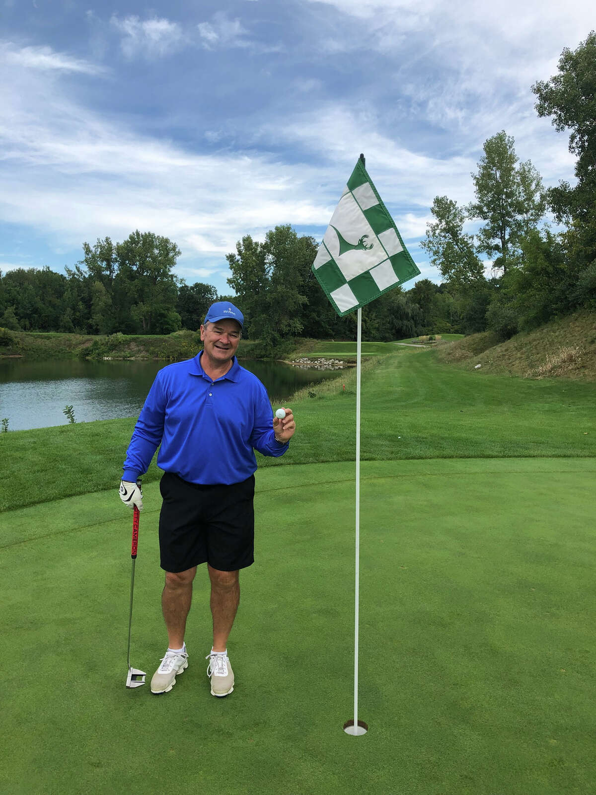 Gary Bryant stands with his golf ball near the cup of the eighth hole at Bucks Run, where he shot his second hole-in-one in three days recently.