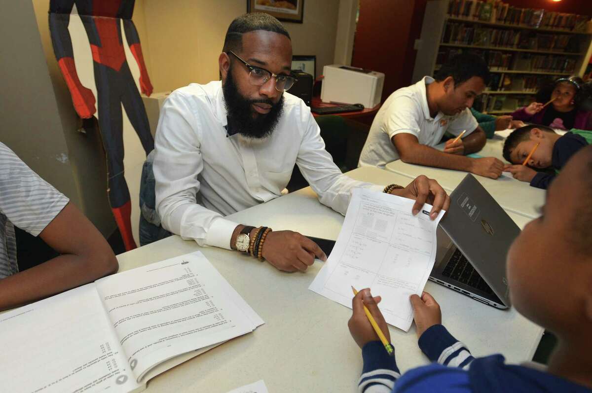 Counselor Donavan Tracey helps kids with their math skills at the South Norwalk branch of the Norwalk Public Library on Tuesday.