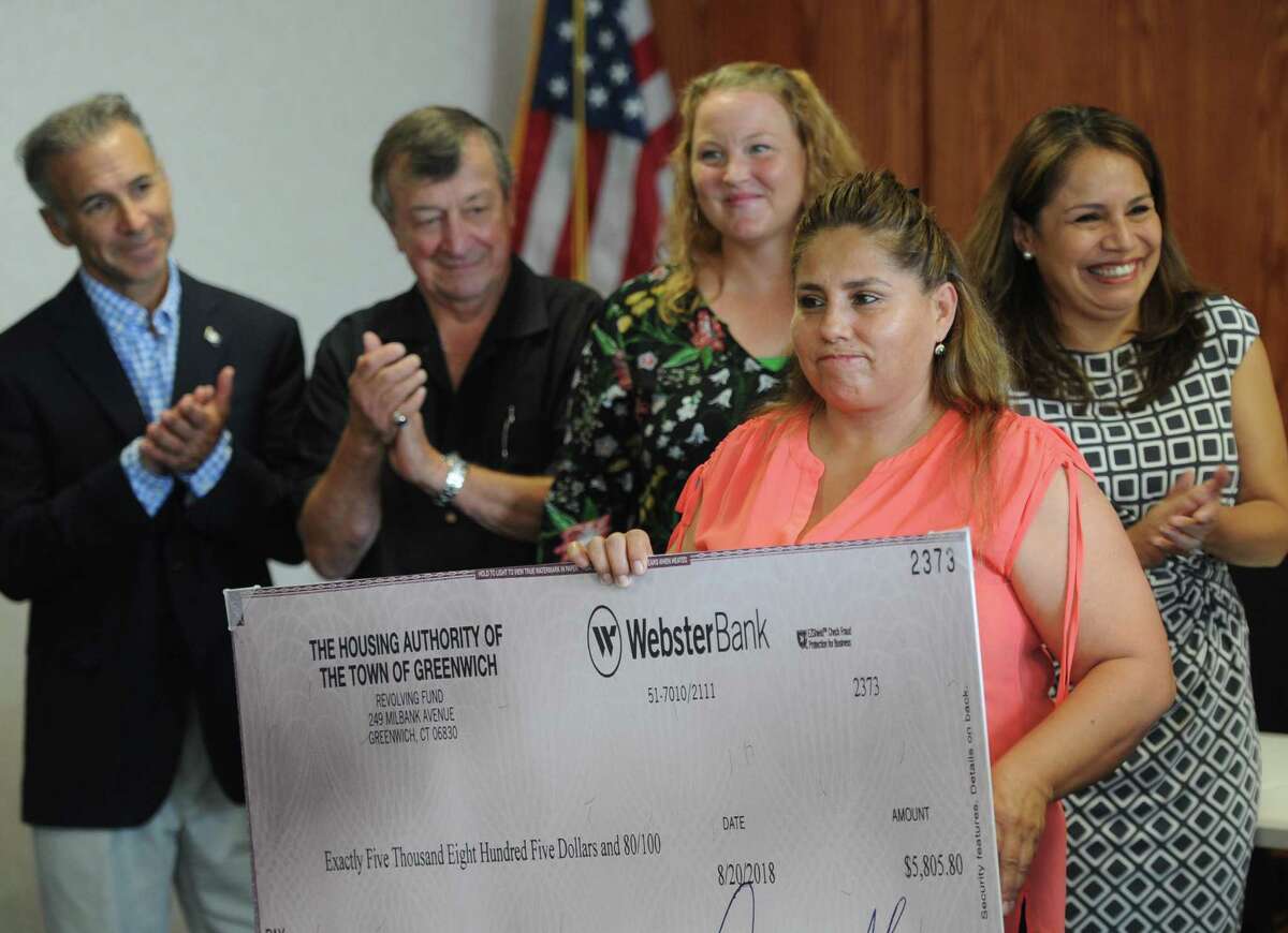 Wilbur Peck public housing resident Narciza Rey accepts a check for $5,805.80 during the Greenwich Housing Authority's Family Self Sufficiency Program check presentation at Town Hall in Greenwich, Conn. Thursday, Sept. 13, 2018. Two Greenwich public housing residents received checks from a special Housing Authority escrow savings account that they've been paying into for the last five years.