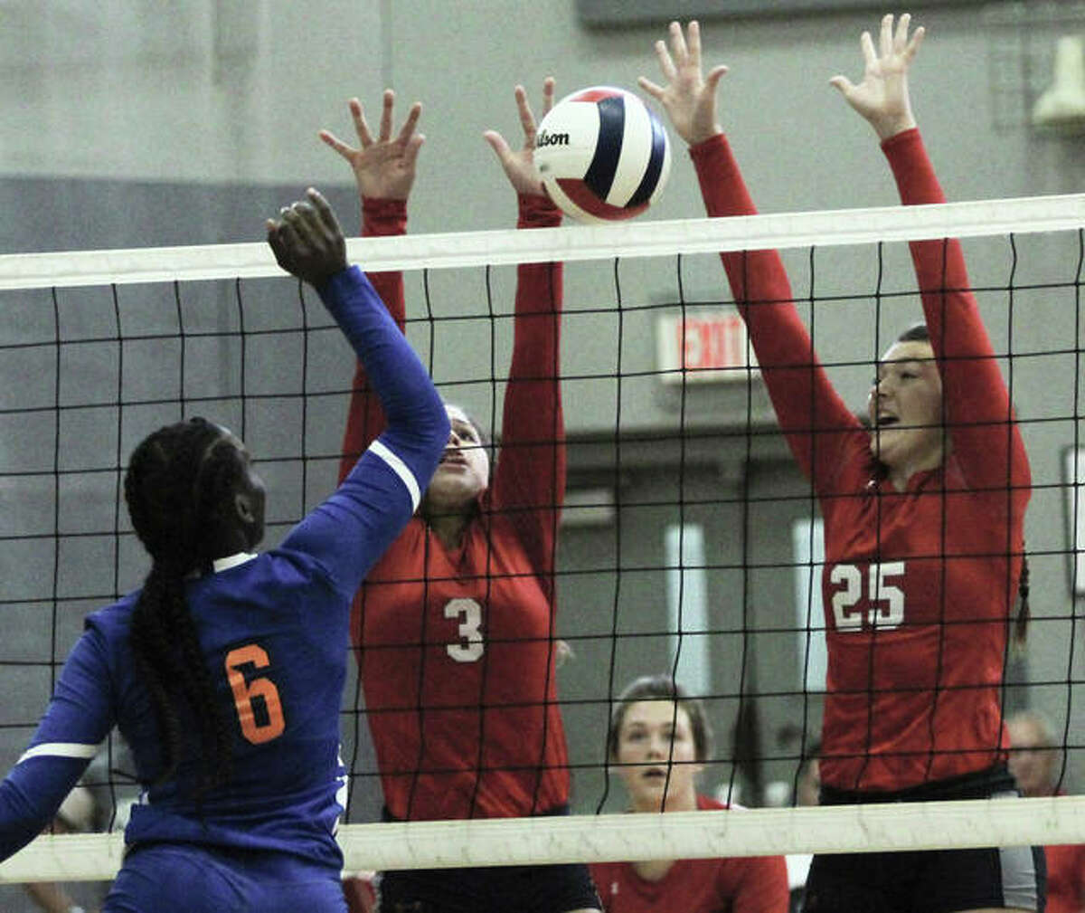 East St. Louis’ Michaela Hines (6) hits into the block put up by Alton’s Shiann Johnson and Brooke Wolff (25) on Thursday night in Godfrey.