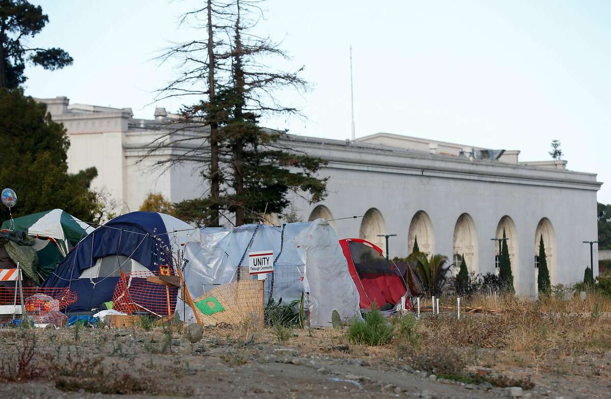 A homeless encampment occupies a vacant parcel slated for development at Lake Merritt Boulevard and East 12th Street near the Kaiser Convention Center (background) in Oakland, Calif. on Thursday, Sept. 13, 2018.