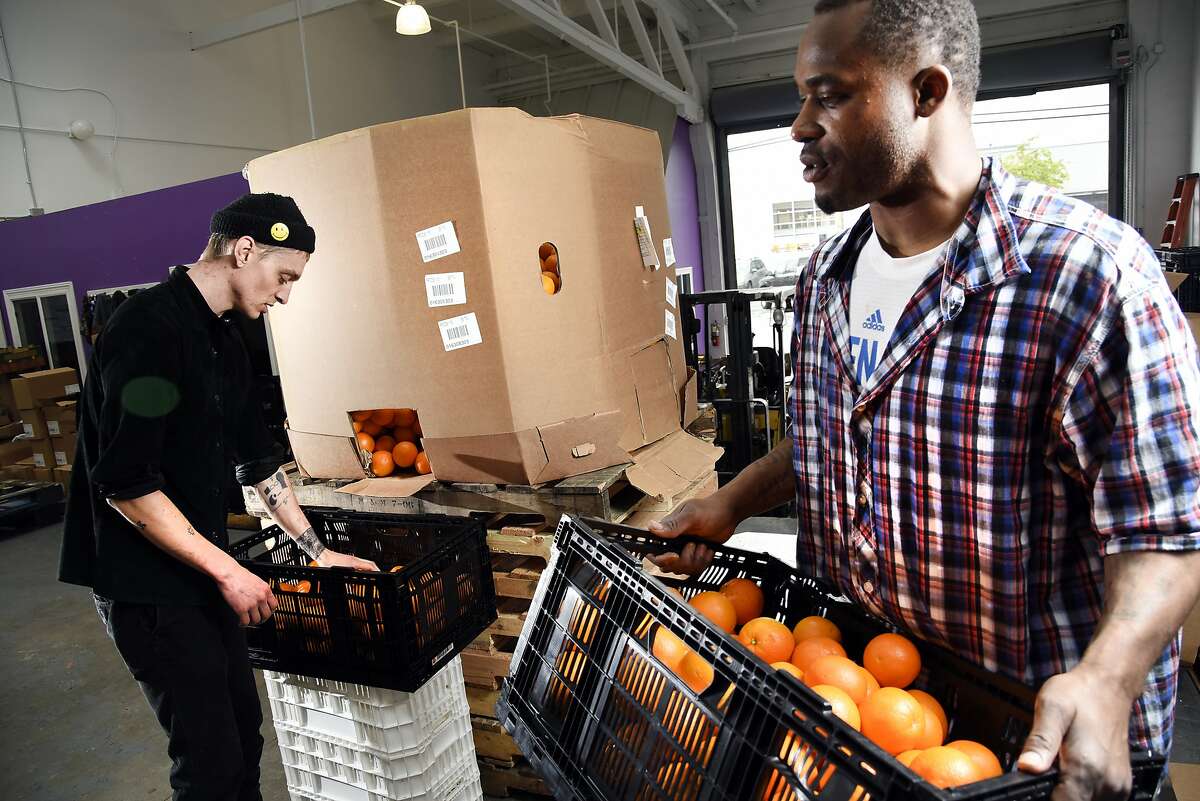 Operation assistants Dallin Kapp, left, and Jonel Jimmerson sort through oranges that are bought as waste from a grower and are then divided up according to their saleability at Imperfect Produce's warehouse in Emeryville, CA, Wednesday March 9, 2016.