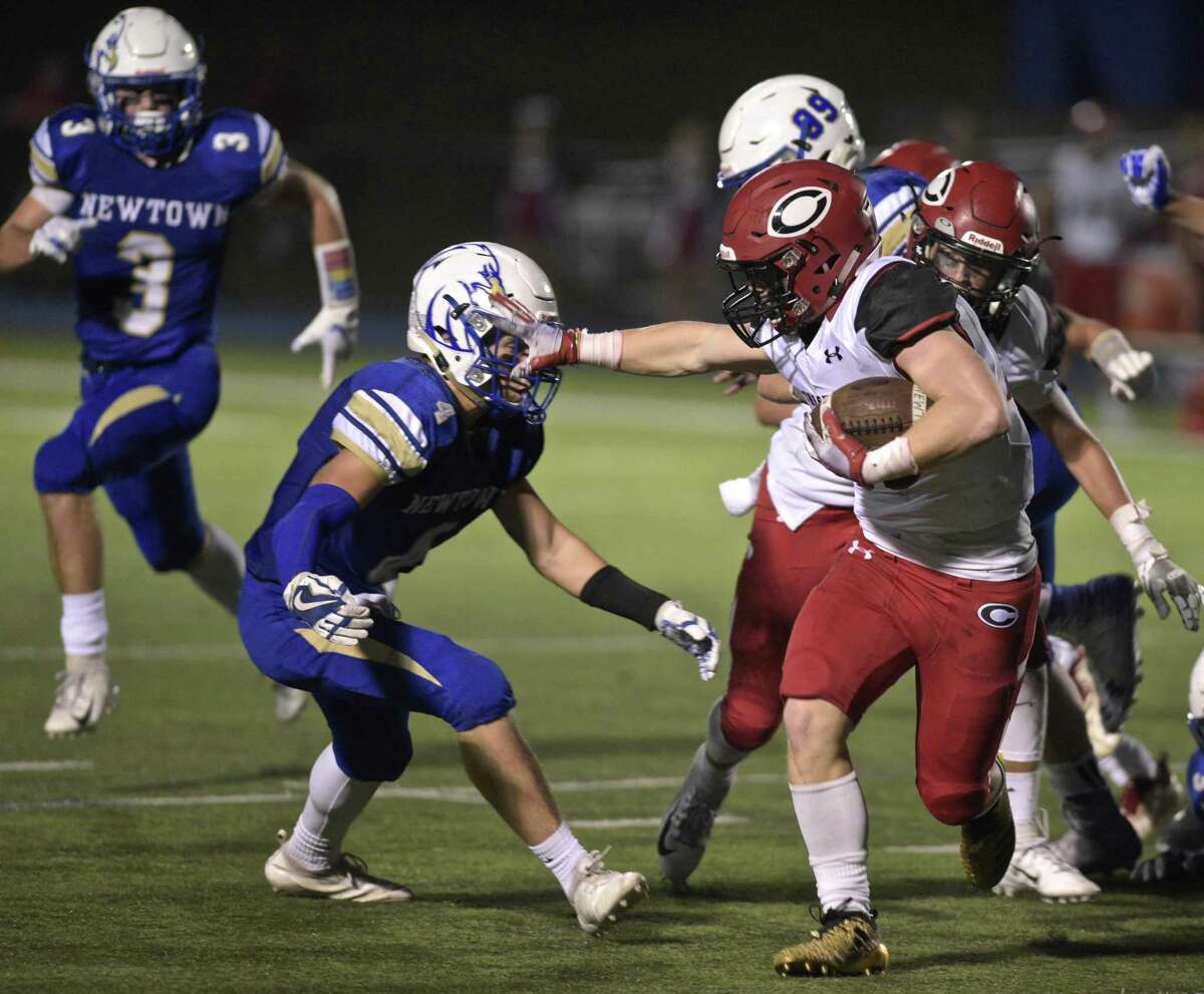 Cheshire's Jake McAlinden (43) stiff arms Newtown's Jack Zingaro (4) as he comes through the line in the football game between Cheshire and Newtown high schools, Friday night, September 14m 2018, at Newtown High School, in Newtown, Conn.