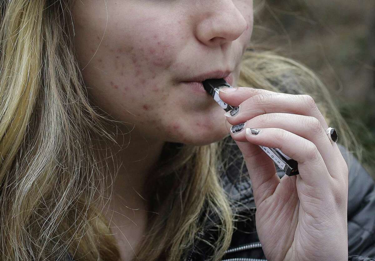 In this April 11, 2018, file photo, an unidentified 15-year-old high school student uses a vaping device near the school's campus in Cambridge, Mass. A school-based survey shows nearly 1 in 11 U.S. students have used marijuana in electronic cigarettes, heightening concern about the new popularity of vaping among teens. E-cigarettes typically contain nicotine, but results published Monday, Sept. 17, mean a little more than 2 million middle and high school students have used the devices to get high.