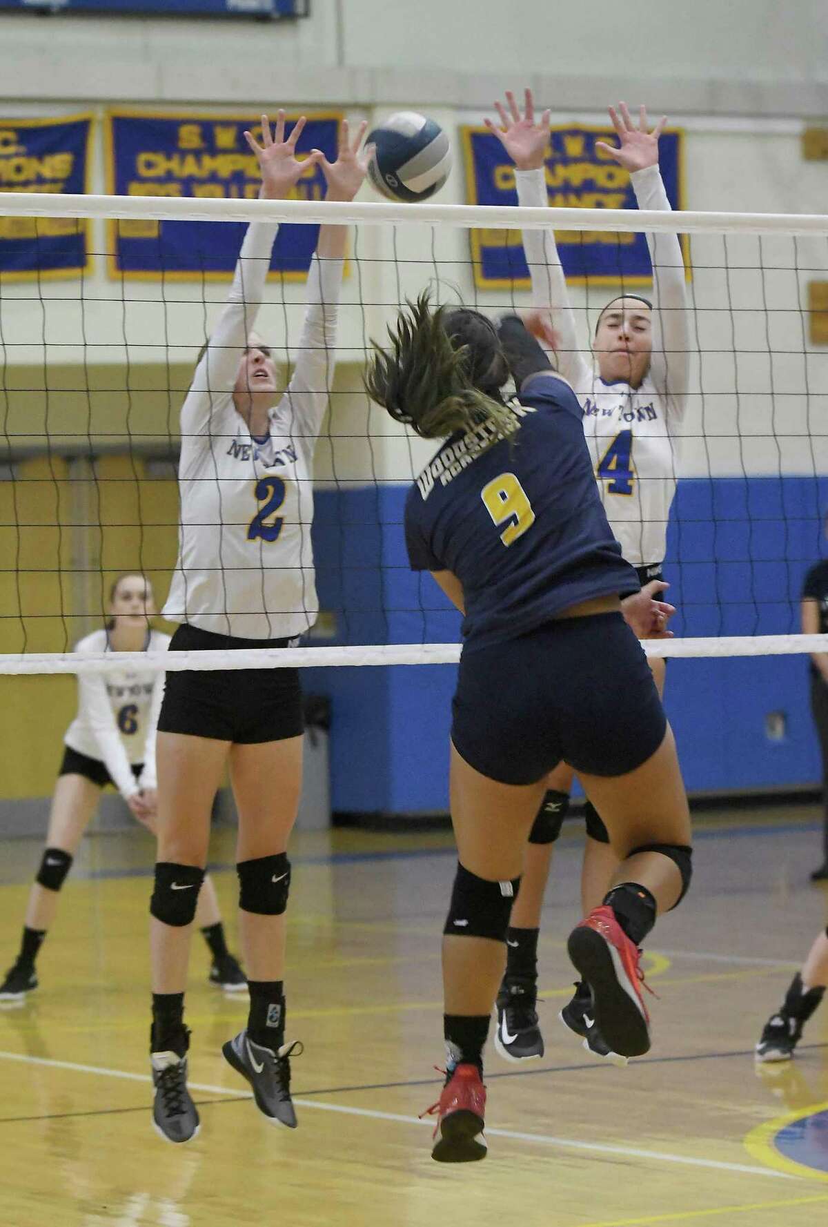 Woodstock Academy?’s Paula Hernandez (9) spikes the ball past Newtown?’s Hannah Groonell, left, and Veronica Kroha (4) during the Woodstock Academy at Newtown High School girls volleyball game, Sept. 17, 2018.