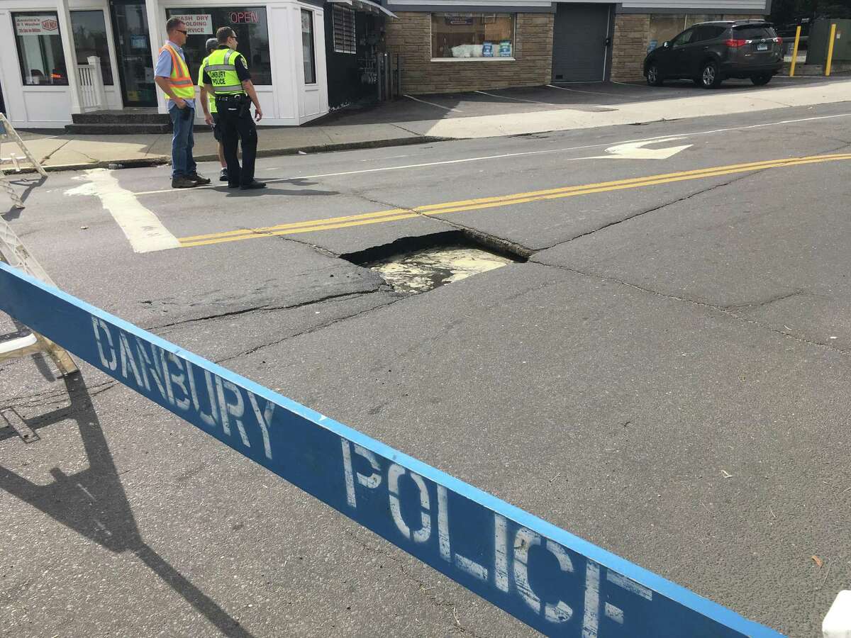 Danbury police officers stand near a sinkhole that opened Wednesday on Franklin Street.