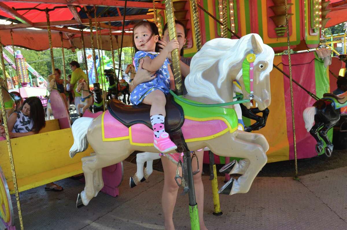 Angela Cao is held by her mom Catherine as they ride the carousel during the Wilton Rotary Club annual family carnival on Sunday September 16, 2018 in Wilton Conn. The event is a fundraiser that benefits the Wilton Rotary Club's community improvement projects both locally and internationally.