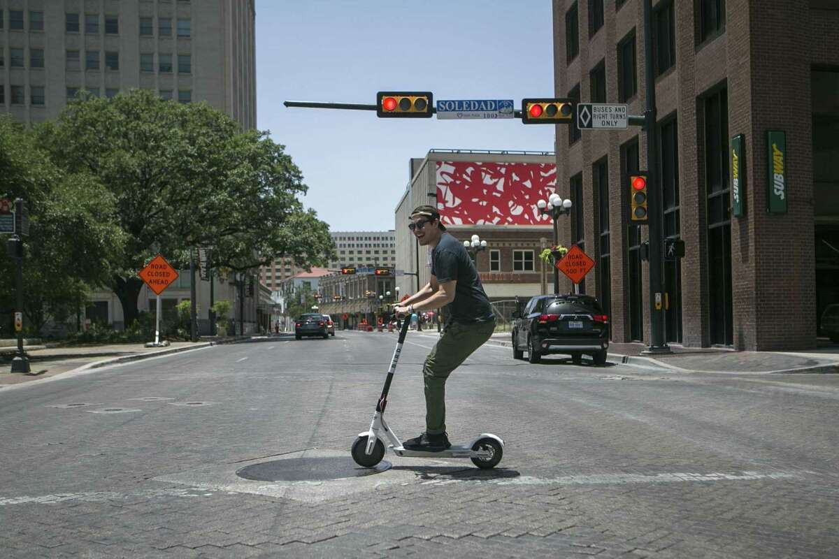 Marty Lind of Austin crosses Commerce Street in downtown San Antonio on an electric Bird scooter on July 1, 2018.
