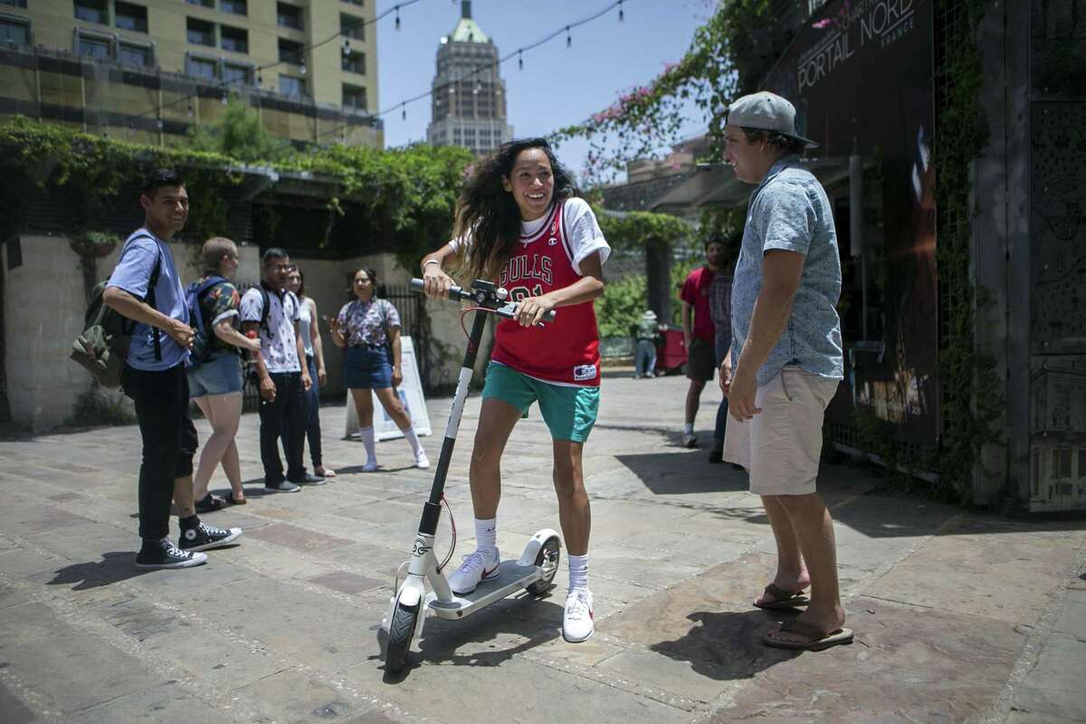 April Galindo of Austin hops on an electric Bird scooter in Main Plaza in downtown San Antonio on July 1, 2018. There are several thousand in the city now.