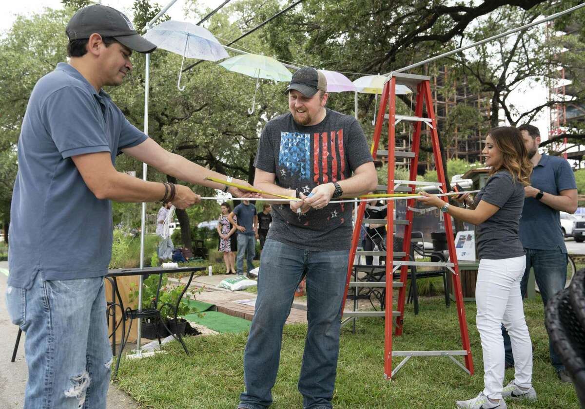 Ford, Powell & Carson architect Oscar Reyes (left) helps designers Jeremy Kreusel (center) and Michelle Garcia set up the firm’s tiny urban park along McCullough Avenue downtown. The display was part of the national PARK(ing) Day event, which transforms concrete parking spaces into small parks in an effort to make urban spaces more inviting and walkable.