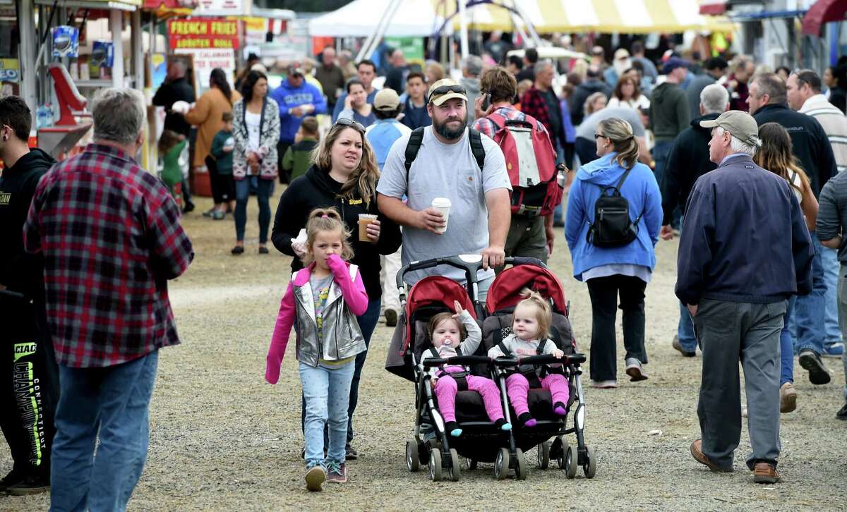 Wayne Volpe (center) of Guilford makes his way through an aisle of food vendors with his wife, Allison, and 15-month-old twins, Alayna and Alyssa, at the 160th annual Guilford Fair on September 23, 2018.