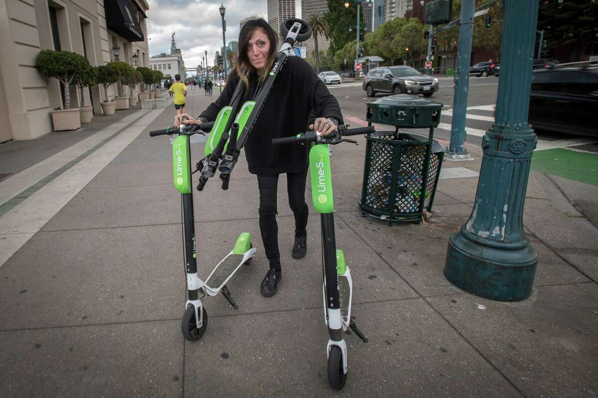 Livia Looper pushes LimeBike scooters in San Francisco on May 15, 2018.