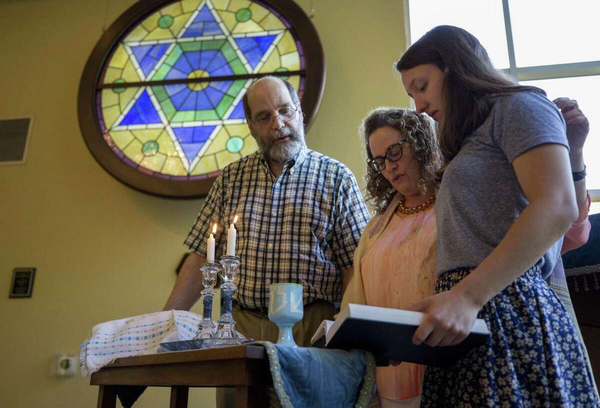 Rabbi Deborah Schloss, center, is joined by her husband, Eljay Waldman, and her daughter, Priya Schloss Fink, as they say the blessing over the lighting of Shabbat candles during the beginning of service at Temple Beth Tikvah in Houston.