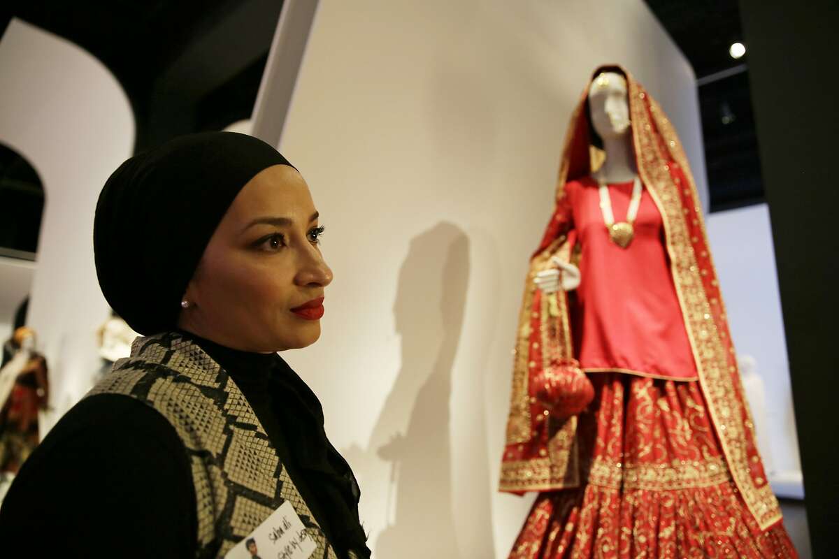 In this photo taken Thursday, Sept. 20, 2018, stylist Saba Ali talks about her Pakistani wedding ensemble of red silk and chiffon in the exhibit Contemporary Muslim Fashions at the M. H. de Young Memorial Museum in San Francisco. The first major museum exhibition of contemporary Muslim women's fashion reflects designs from around the world that are vibrant and elegant, playful and diverse. The show's creators hope the exhibit will show Muslim women as real people who can choose what they wear rather than as subjects ordered to cover their entire bodies or restricted in what they can wear. The exhibit opens on Saturday. (AP Photo/Eric Risberg)