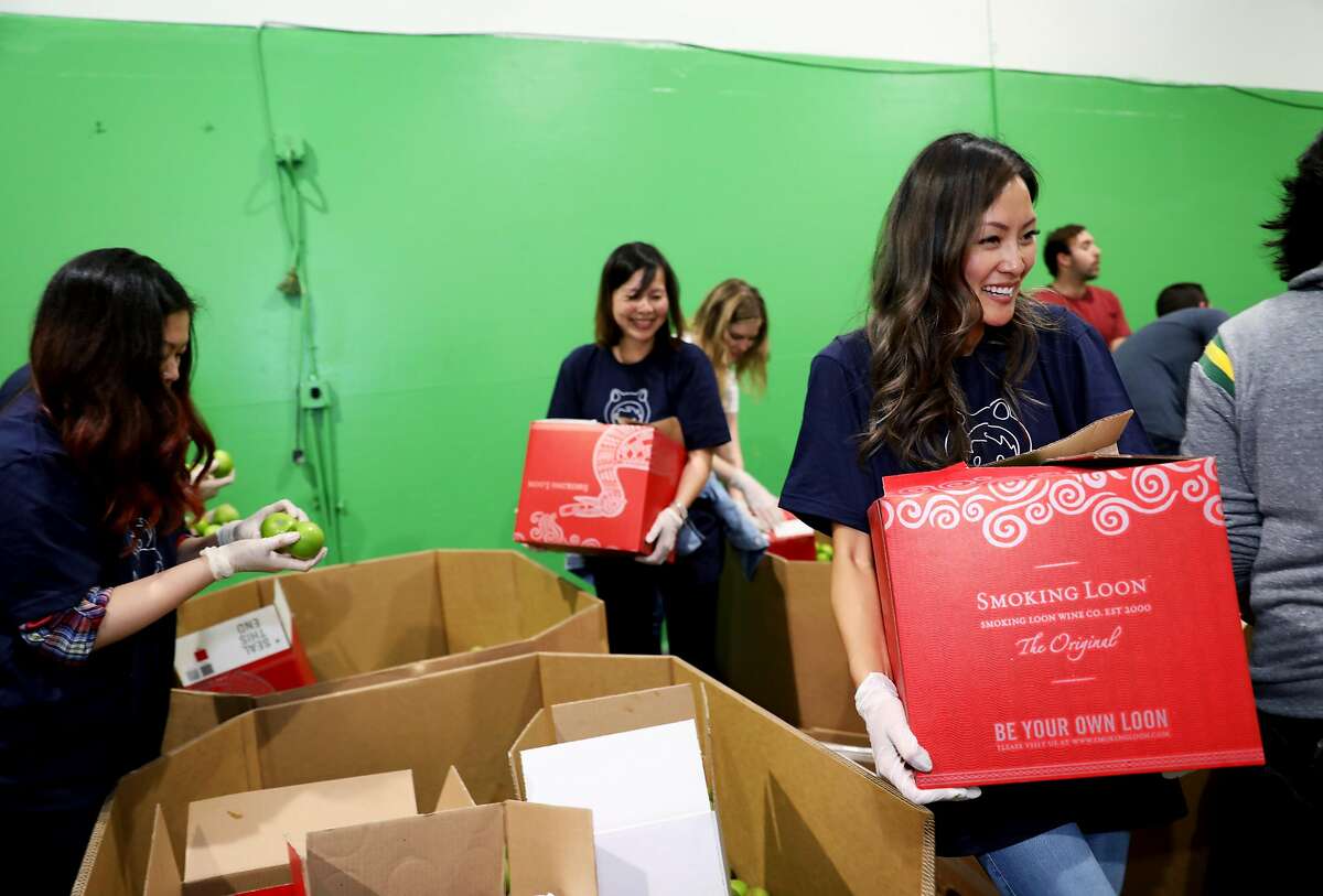 Salesforce employee Erika Ny, an operations team member, carries a packed box of Granny Smith Candy apples at the San Francisco - Marin Food Bank, located at 900 Pennsylvania Ave., in San Francisco, Calif., on Wednesday, September 19, 2018. Salesforce gives its employees a week of PTO for community service and on Wednesday, eleven Salesforce employees used two hours of that time to volunteer at the food bank.