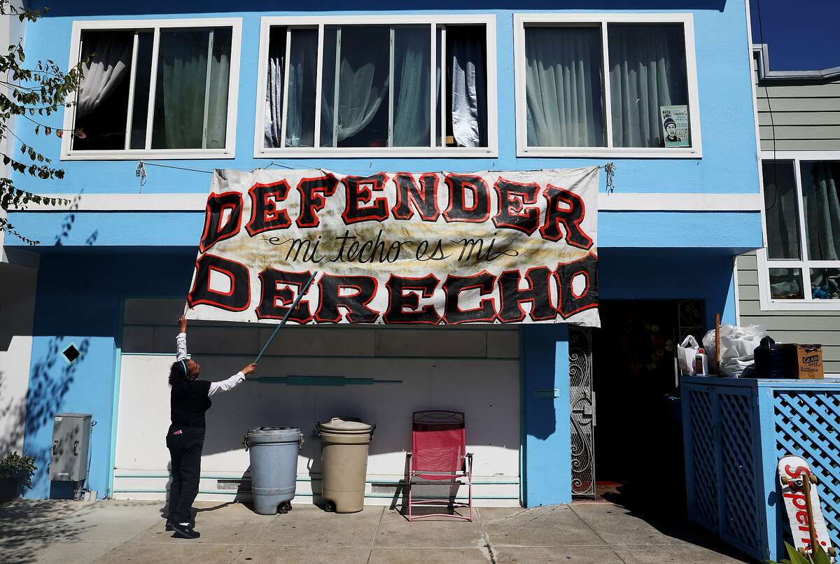 Juana Ines Tello straightens a banner that reads "Defending my roof is my right" in front of her home at 1778 Newcomb Ave., in the Bayview District, in San Francisco, Calif., on Wednesday, September 19, 2018. "We're still here," Tello, 70, said. "We're in a battle. We're in the struggle and it's an every day struggle and we're all in it together." Tello and her family were evicted from their home of 18 years the following morning. According to family members, about 30 officers from the San Francisco Sheriff's Department arrived with two vans, five SUVs, and five police cruisers when they barged into the Tello's home at 8:30 a.m. The family is currently staying with a relative until they can find housing.
