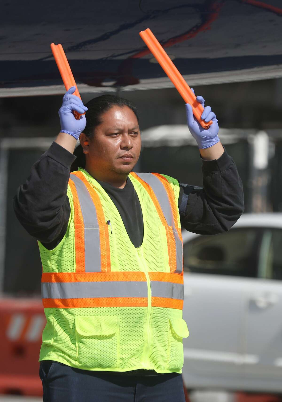 A ground air transportation employee guides a vehicle working on a plane that just landed on Thursday, Sept. 6, 2018 in San Francisco, Calif. Recent contract negotiations between the city and unionized SFO workers resulted in higher minimum wages.