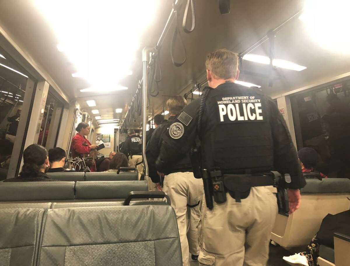 At least eight armed, uniformed DHS officials walk in the aisle among seated passengers on a BART train bound for the Civic Center BART station in San Francisco on Tuesday, Sept. 25, 2018.