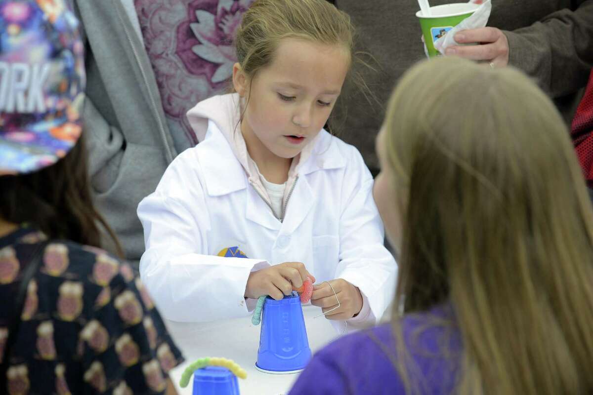 In this file photo, Emily Brandt attempts to put a gummy ring around a gummy worm without using her hands at STEMFest in Mill River Park. This Sunday, the free, daylong festival will feature hands-on science, technology, engineering and math activities for all ages.