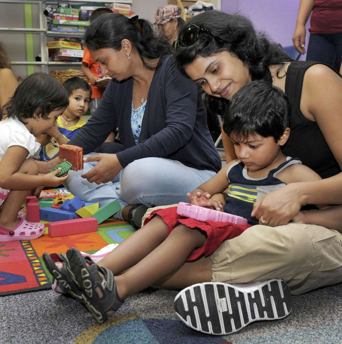 Lipsa Panda, right, and son Aaron Mohapatra, 3, play an electronic game during a weekly class offered by The United Way of Western Connecticut, Wednesday, June 10. Left is Kavita Desai and daughter Aashi, 2 1/2. The class, held at the Danbury Library, is a pilot program for the largely-Latino neighborhood around the Park Avenue Elementary School to teach parents how to be the primary educators of their children.