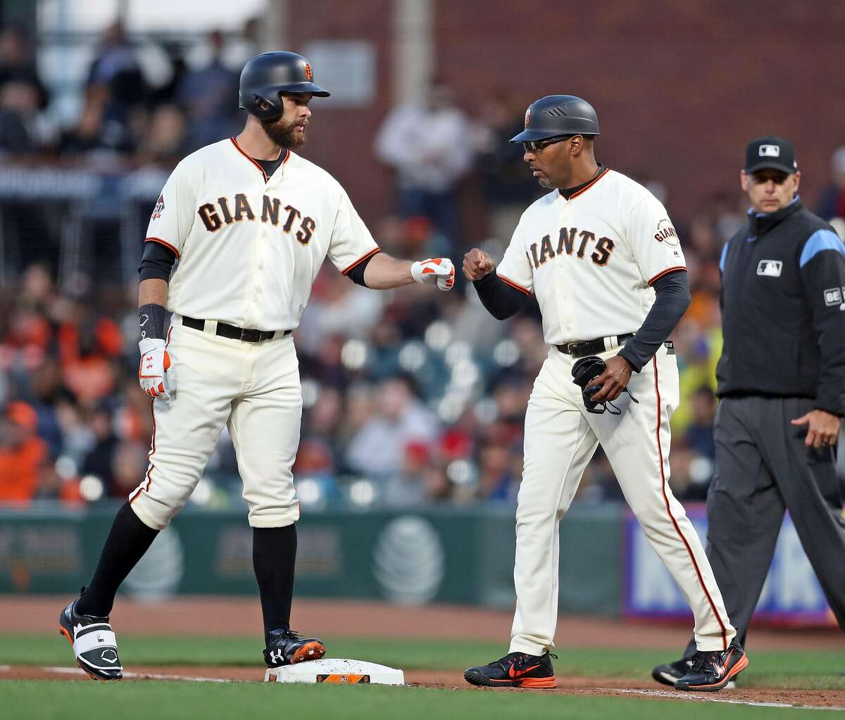San Francisco Giants' first base coach Roberto Kelly fist bumps Brandon Belt after Belt's 4th inning single against Miami Marlins during MLB game at AT&T Park in San Francisco, Calif. on Monday, June18, 2018.