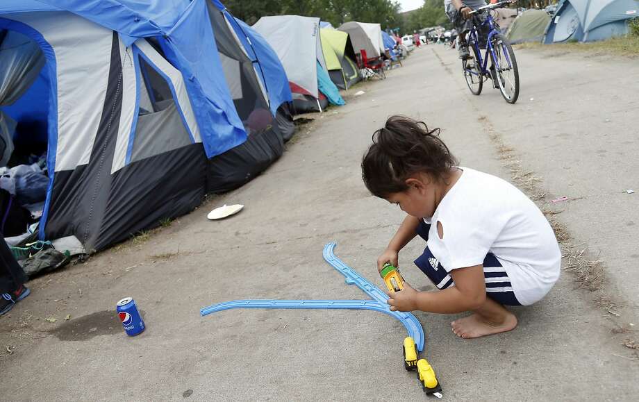 Four-year-old Koda Deer plays with a small train in front of the family tent in a homeless camp south of Minneapolis. Officials voted to approve a temporary site to accommodate hundreds of people. Photo: Jim Mone / Associated Press