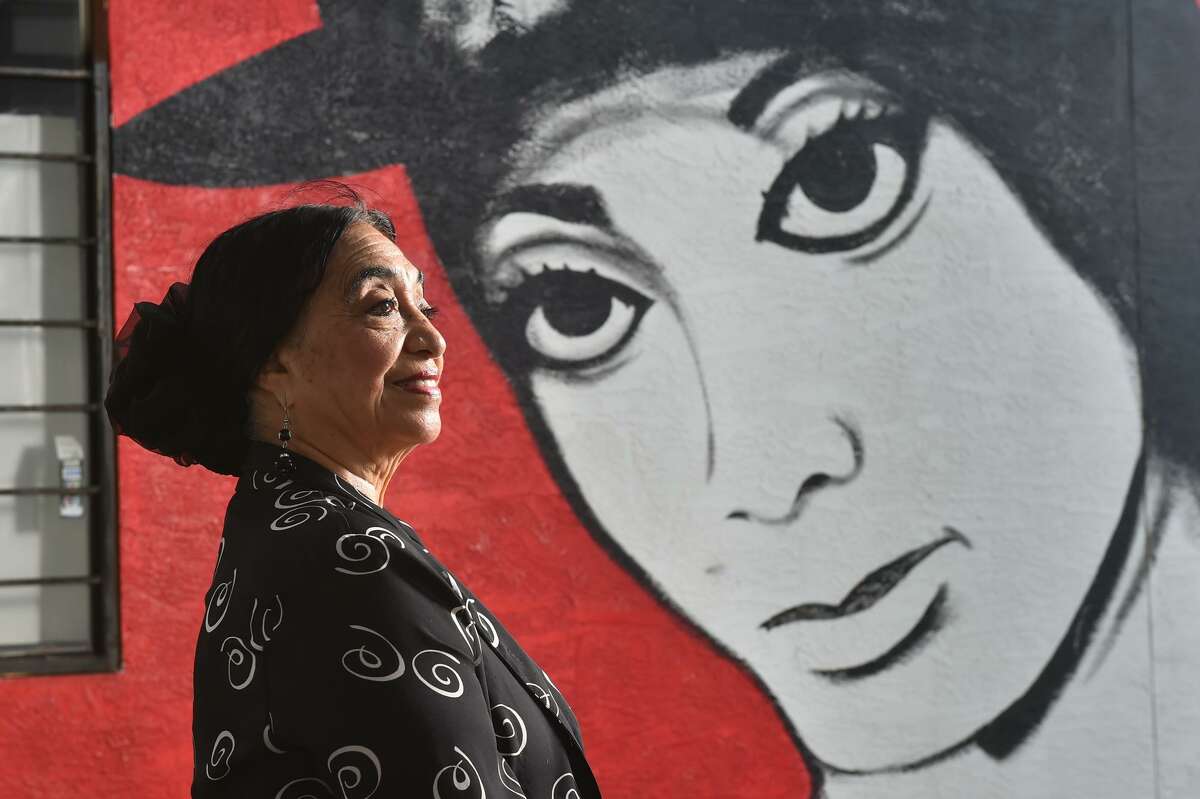 Teresa Champion, who has been teaching flamenco dance for decades, stands beside a mural depicting her that Ronald Rocha is painting on the side of her dance studio. Champion, 79, is being honored during the WeFlamenco Fest.