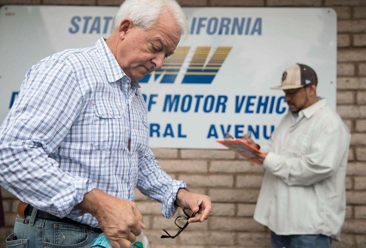 Republican Governor candidate John Cox hands out bottles of water to people in line during a stop on his state-wide tour at the Central Fremont DMV in Fremont, Calif. Friday, Sept. 28, 2018.