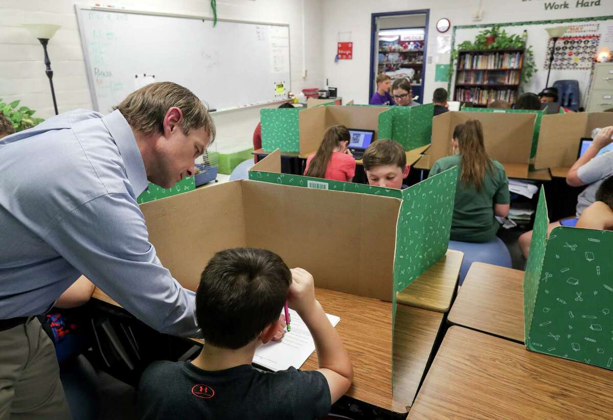 Steven Horelica, the mayor-elect of Devers, Texas, and the fifth grade teacher at Devers Elementary School, works with Kody Sandefer, 11, in his classroom, May 8. Adding school days will be costly, money that might be better spent on other measures to improve schools.