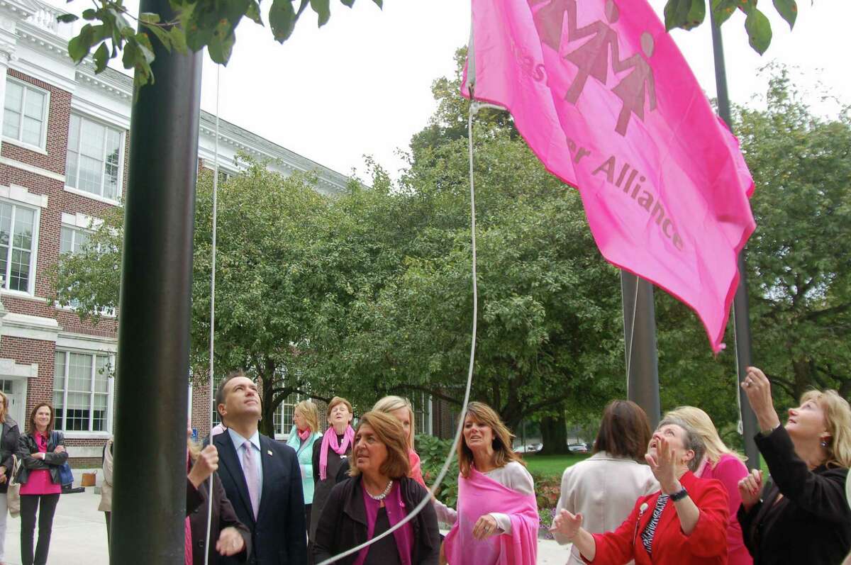 Breast Cancer Alliance and its supporters, including First Selectman Peter Tesei, raise the pink flag in front of Town Hall in a previous year. Greenwich will mark Breast Cancer Awareness Month throughout October.
