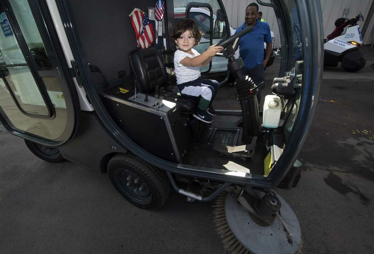 Kevin Arita, 22 months from Norwalk, sits in a Norwalk Parking Authrity Sweeper while Authority employee B.K. Mebrahtu looks on during The Norwalk Fire, DPW, Police, and EMS Open House and Touch-a-Truck event Saturday, September 29, 2018, at the Department of Public Works facility on South Smith Street in Norwalk, Conn.
