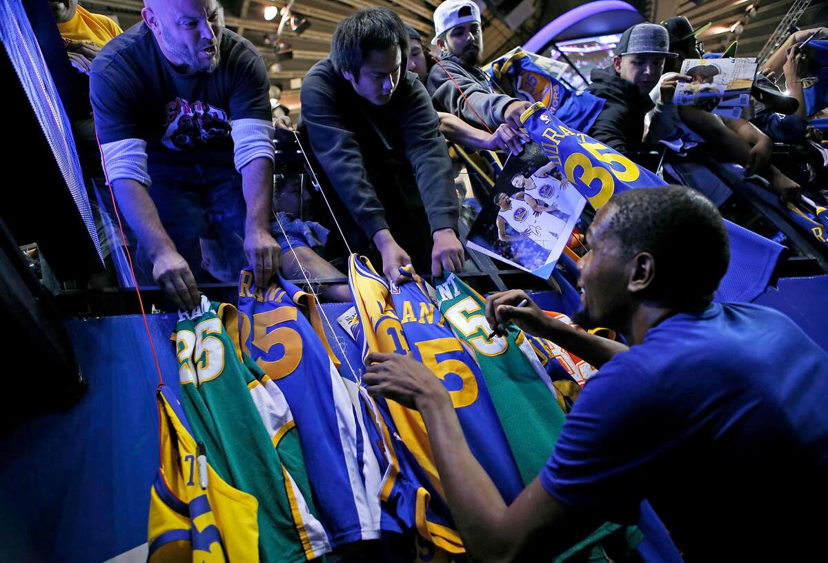 Golden State Warriors forward Kevin Durant (35) signs autographs before heading into the locker room after warming up before an NBA preseason game between the Golden State Warriors and Minnesota Timberwolves at Oracle Arena on Saturday, Sept. 29, 2018, in Oakland, Calif.