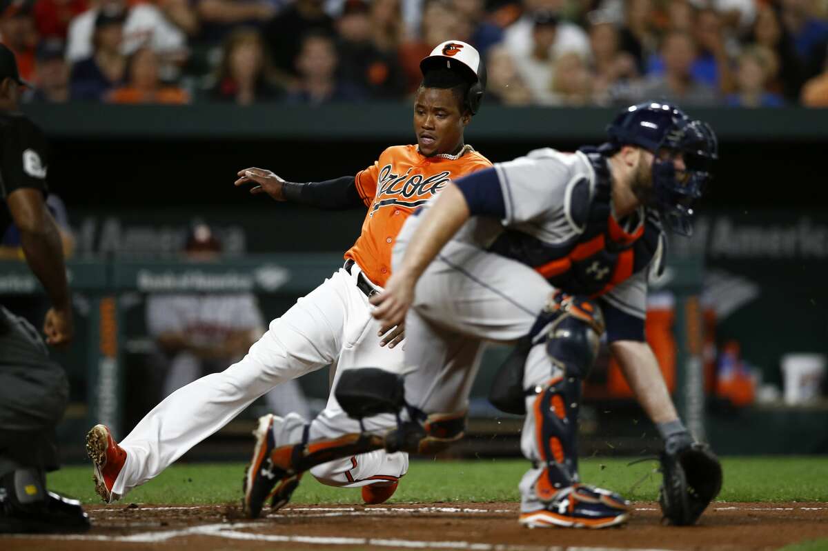 Baltimore Orioles' Tim Beckham slides safely across home plate past Houston Astros catcher Brian McCann for a run on Austin Wynns' single in the second inning of the second baseball game of a doubleheader, Saturday, Sept. 29, 2018, in Baltimore. (AP Photo/Patrick Semansky)