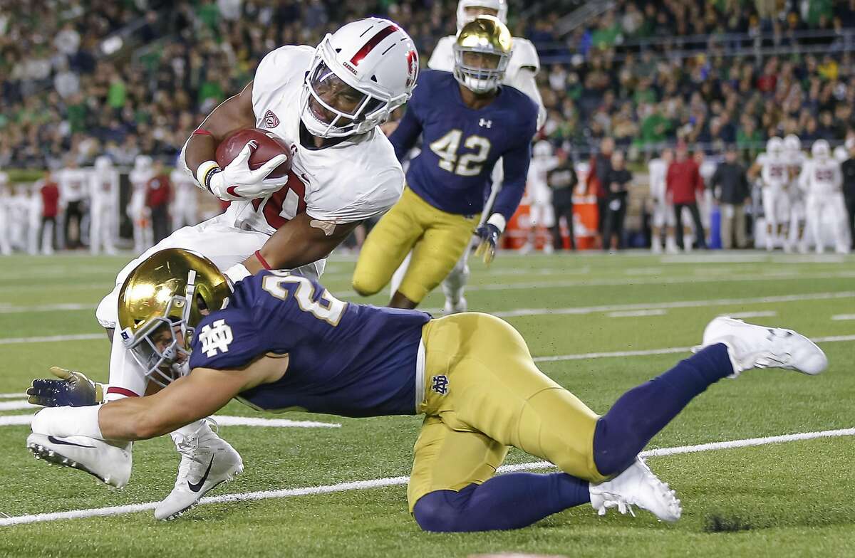 SOUTH BEND, IN - SEPTEMBER 29: Bryce Love #20 of the Stanford Cardina runs the ball and is tackled by Drue Tranquill #23 of the Notre Dame Fighting Irish during the first half of the game at Notre Dame Stadium on September 29, 2018 in South Bend, Indiana. (Photo by Michael Hickey/Getty Images)